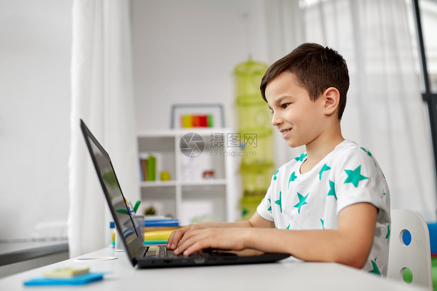教育技术人的微笑的学生男孩家里用笔记本电脑打字学生男孩家用笔记本电脑打字图片