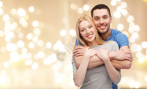 爱,关系人的微笑的夫妇拥抱米色背景与节日灯微笑的夫妇拥抱节日的灯光上图片