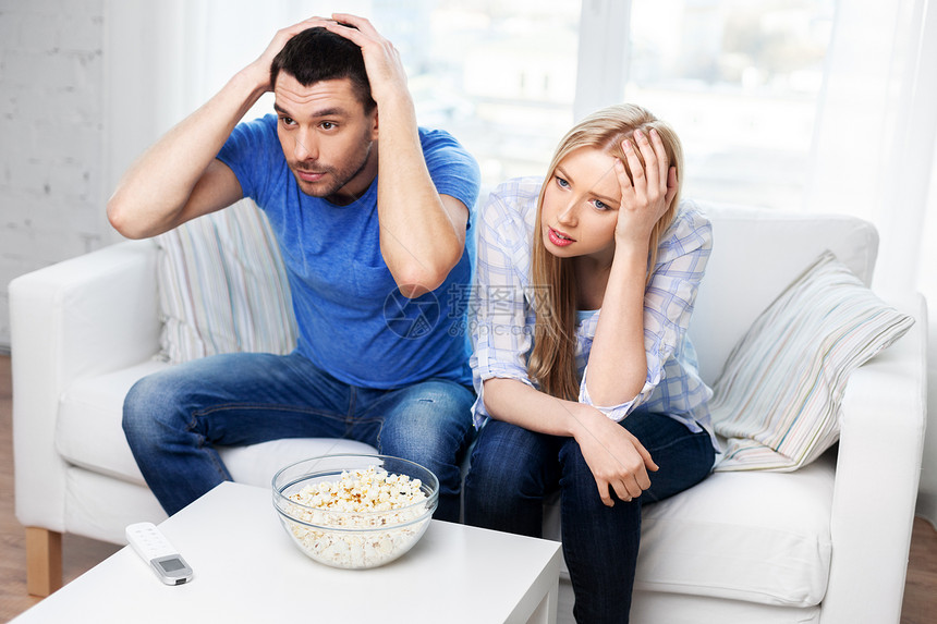 人们,家庭休闲心烦意乱的夫妇家里看电视爆米花家里看电视吃爆米花的夫妇心烦意乱图片