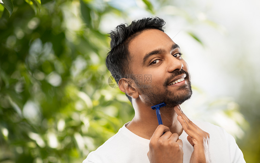 美容人的微笑的印度男子剃须胡须与手动剃须刀刀片绿色的自然背景印度男人用剃须刀刮胡子图片