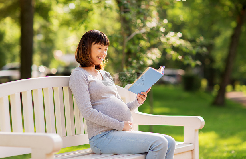 怀孕,人母亲的快乐的怀孕亚洲妇女坐公园长凳上看书快乐怀孕的亚洲妇女公园读书图片