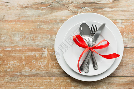 情人节节日晚餐的盘子与勺子,刀叉子绑木制桌子上,顶部餐具用红丝带绑盘子上图片