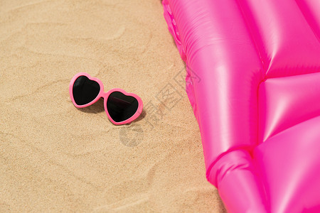 假期暑假的粉红色太阳镜沙滩上的游泳床垫海滩上的太阳镜粉红色游泳床垫图片