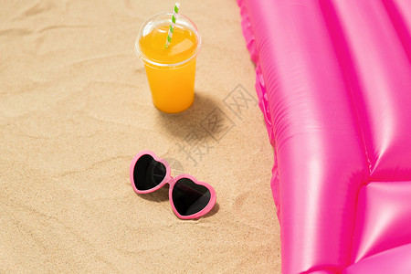 假期暑假的粉红色太阳镜,橙汁海滩沙滩上的游泳床垫太阳镜,果汁海滩沙滩床垫图片