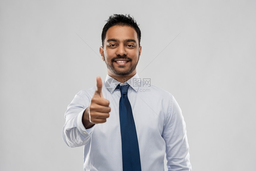 商业,上族人的微笑的印度商人穿着衬衫,带着领带,灰色的背景上竖大拇指印度商人竖大拇指图片