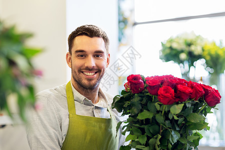 小生意,销售花卉快乐微笑的花店卖家与红玫瑰花店花店里红玫瑰的花店销售商图片