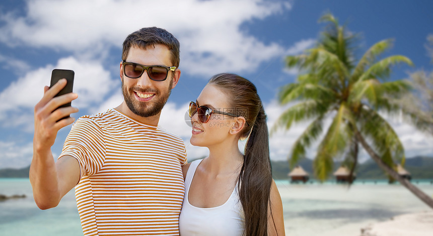 旅行,旅游人们的幸福的夫妇采取智能手机自拍热带海滩背景法属波利尼西亚快乐的夫妇海滩上用智能手机自拍图片