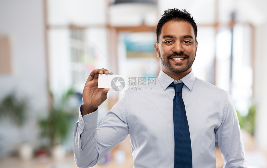 商业人的微笑的印度商人持名片办公室背景印度商人,名片超过办公室图片