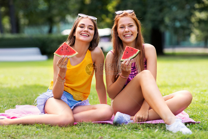 休闲友谊的快乐微笑的十几岁的女孩朋友夏天的公园野餐吃西瓜十几岁的女孩公园野餐时吃西瓜图片