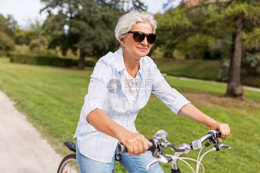 积极的老,人生活方式的快乐的老妇女骑固定自行车夏季公园快乐的高级女人夏季公园骑自行车图片