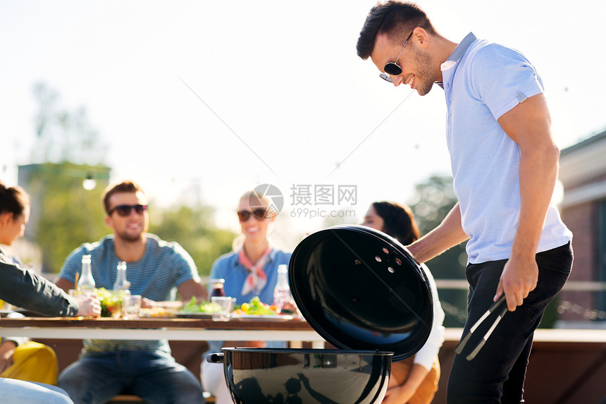 休闲人的快乐的男人烧烤朋友屋顶聚会男人屋顶派上烧烤图片