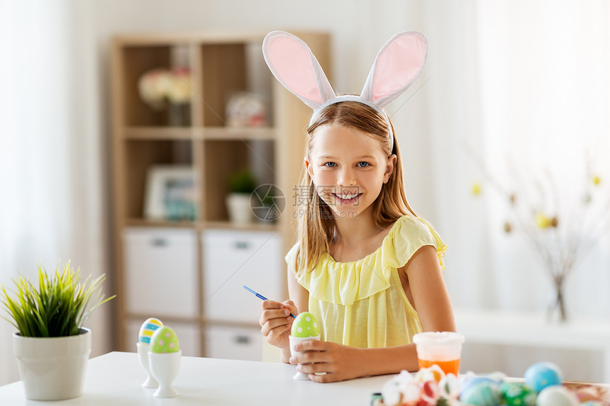 复活节,假日人们的快乐的女孩戴着兔子耳朵,头带着色鸡蛋与颜色刷子家里快乐的女孩家里给复活节彩蛋着色图片