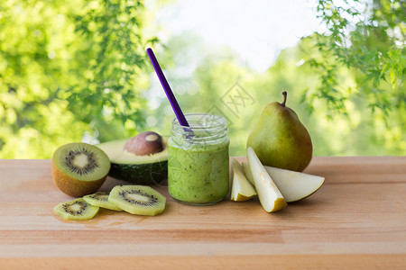 婴儿食品,健康饮食营养璃罐与绿色水果泥木板上的自然背景木板上装水果酱婴儿食品的罐子背景图片