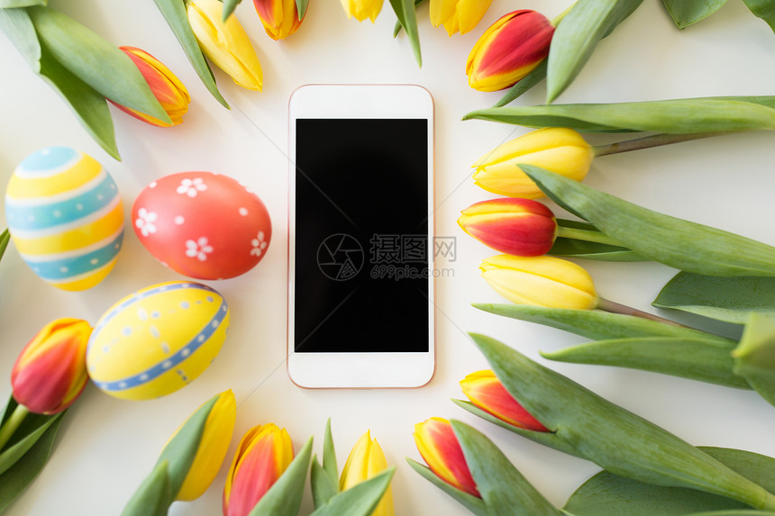 复活节,假日,传统象智能手机与彩色鸡蛋郁金香花白色背景带复活节彩蛋郁金香花的智能手机图片