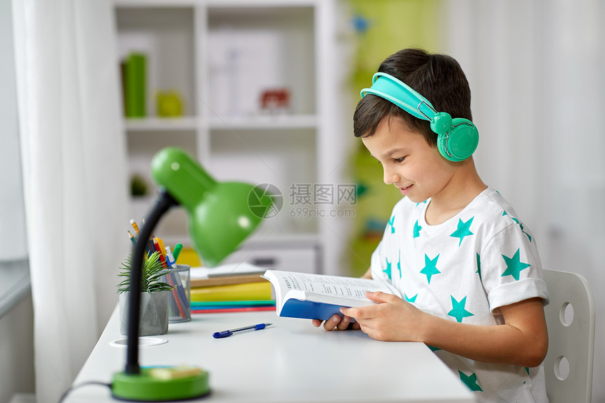 教育,童技术快乐的男孩耳机阅读书家里男孩戴着耳机,家学课本图片