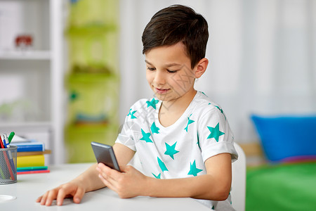 人,技术沟通快乐的微笑男孩与智能手机家里家里智能手机的快乐男孩图片