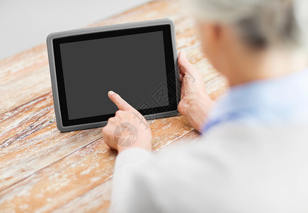 技术老人的老年女子指着平板电脑的空白屏幕平板电脑上黑屏的高级女人图片