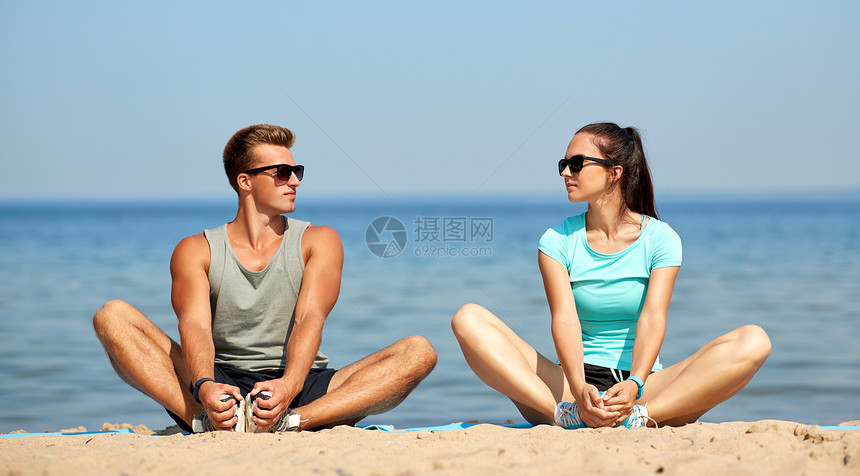 健身,运动生活方式的微笑夫妇伸展腿海滩上训练前微笑的情侣海滩上伸展腿图片