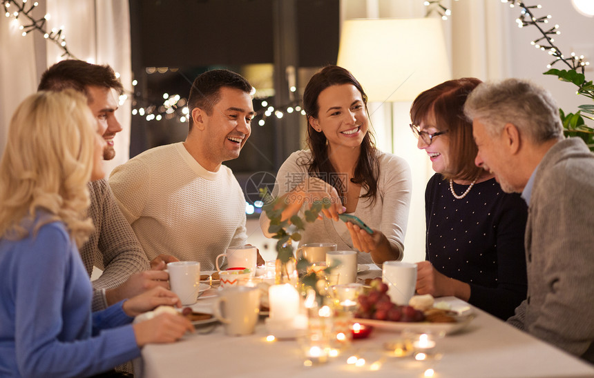庆祝,假日人们的幸福的家庭与智能手机家里举行茶话会家里智能手机的幸福家庭图片