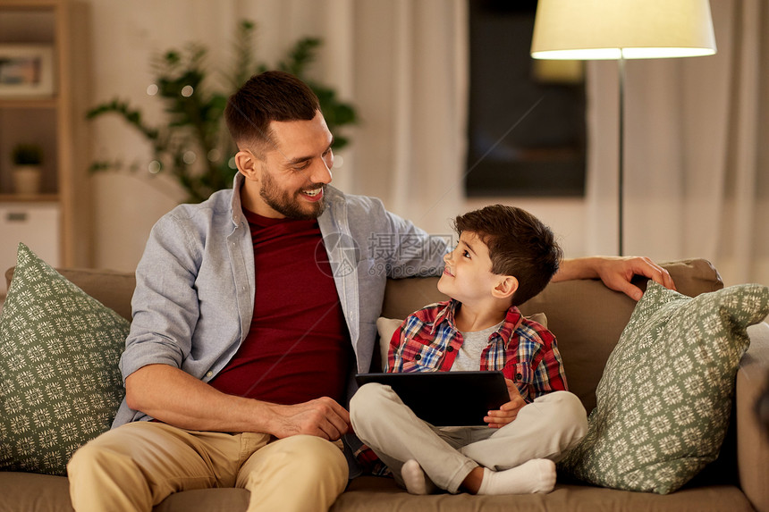 家庭,父亲,技术人的快乐的父亲小儿子与平板电脑电脑坐家里的沙发上父子俩家里玩平板电脑图片