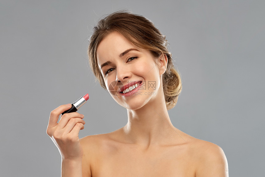 美丽,化妆化妆品的微笑的轻女人灰色背景上涂粉红色口红涂粉红色口红的女人化妆图片