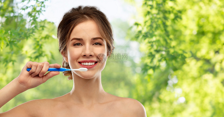 口腔护理,牙科卫生人的微笑的女人用牙刷清洁牙齿绿色的自然背景微笑的女人用牙刷清洁牙齿图片