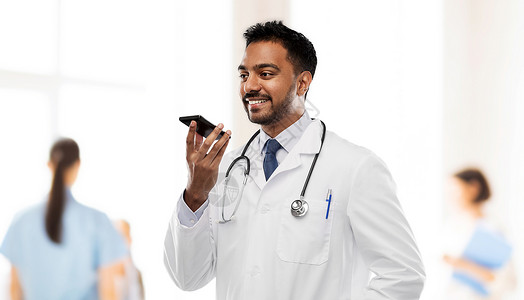 胎音听诊器医学,技术医疗微笑的印度男医生穿着白色外套,带听诊器,医院背景下用语音命令记录器微笑的印度男医生打电话给智能背景