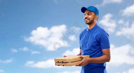 天空盒服务人的快乐的印度送货人与比萨饼盒蓝色制服天空云背景快乐的印度送货人带着蓝色的披萨盒背景