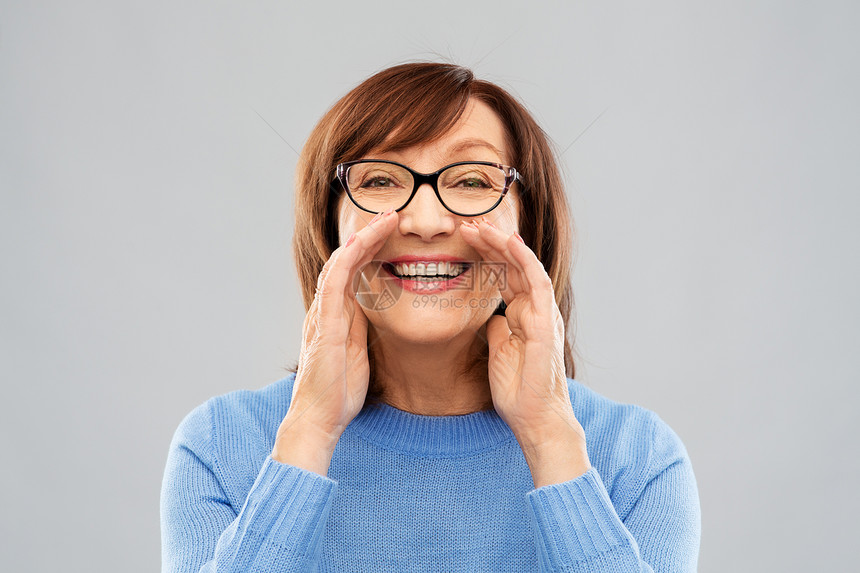 微笑的老年女性表示扩音的手势图片
