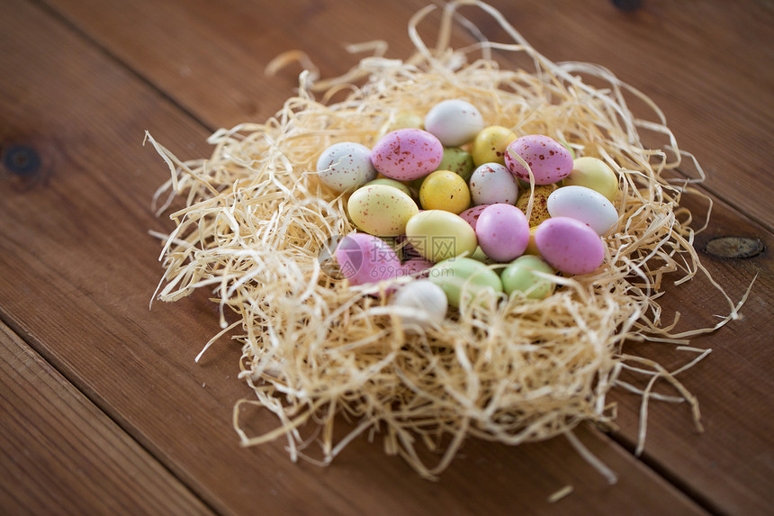 复活节,糖果假日糖果滴鸡蛋稻草巢木桌子上草窝里的复活节彩蛋放木桌上图片