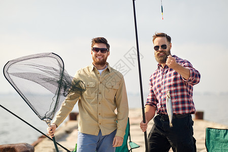 休闲人的快乐的朋友与鱼竿,鱼钓具码头海上鱼竿鱼钓具的朋友码头上背景图片