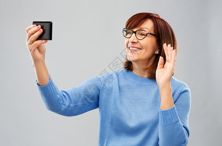 微笑的老年女性使用智能手机视频聊天图片