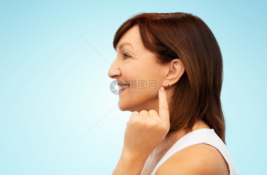 蓝色背景上的女性指着自己的耳环图片