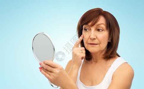 微笑的老年女人在使用镜子观察自己图片