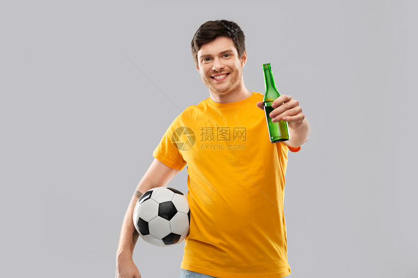 运动,休闲游戏人快乐的人足球迷黄色T恤与足球啤酒瓶灰色背景带足球啤酒的男人足球迷图片