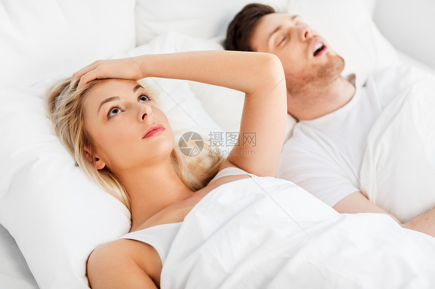 睡眠问题人们的快乐的女人躺床上打鼾的男人快乐的女人躺床上,打鼾的睡着的男人图片