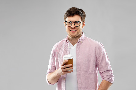 外卖人们的轻人戴眼镜的学生灰色背景下喝咖啡戴眼镜喝咖啡的轻人学生图片
