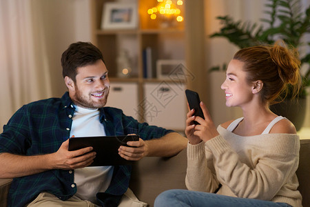 休闲,技术人的快乐的夫妇与平板电脑智能手机家里晚上家里平板电脑智能手机图片