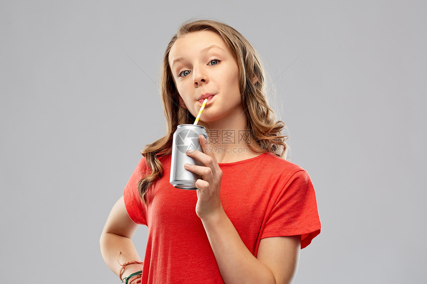 饮料人的十几岁的女孩穿着红色T恤,喝汽水,罐头纸吸管灰色背景女孩纸吸管罐子里喝苏打水图片
