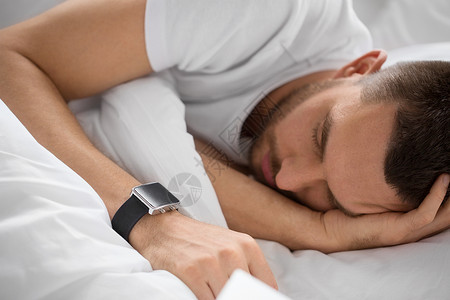 人,技术休息的近距离的人与智能手表睡床上用智能手表床上睡觉的男人图片