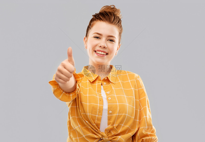 手势人们的微笑的红头发少女穿着格子衬衫,灰色背景上竖大拇指微笑的红头发少女竖大拇指图片