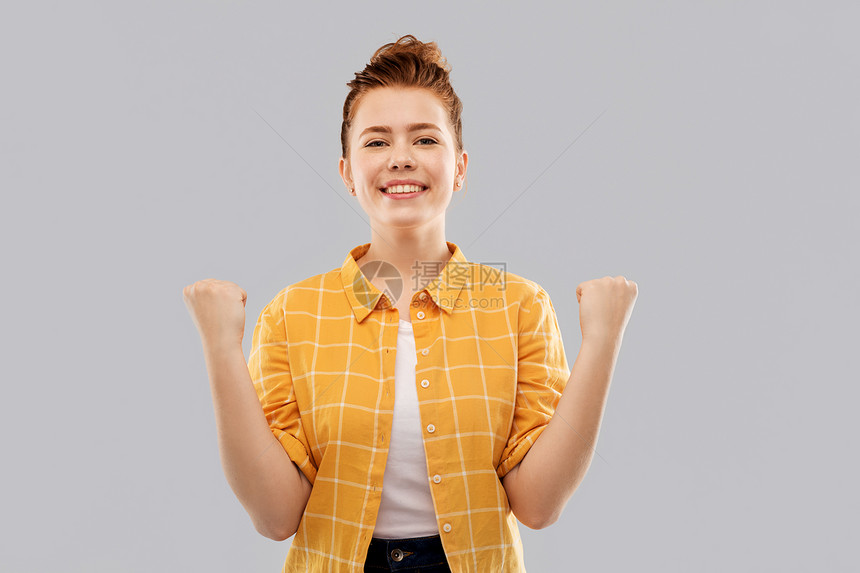 成功,权力人的微笑的红头发少女穿着格子衬衫庆祝胜利的灰色背景快乐的红发少女庆祝成功图片