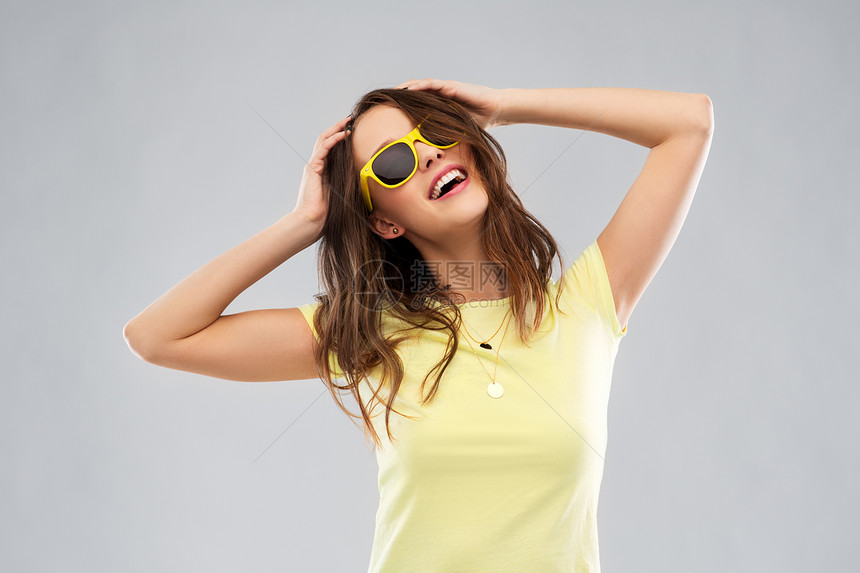 夏天,配饰人的微笑的轻女人十几岁的女孩穿着T恤太阳镜,灰色的背景抱着她的头穿着黄色太阳镜t恤的十几岁图片
