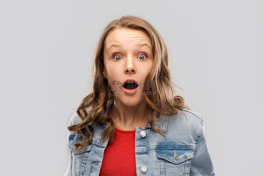 情感,表情人的惊讶震惊的十几岁的女孩张开嘴红色T恤灰色背景穿着红色T恤的十几岁女孩感惊讶震惊图片