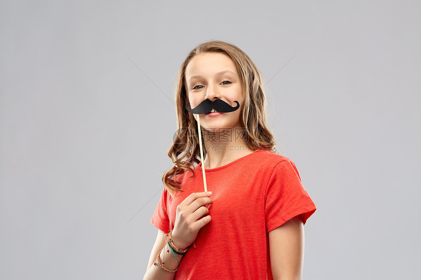 派道具,照片亭人的微笑的十几岁女孩穿着红色T恤,灰色背景上老式的胡子微笑的十几岁女孩带着胡子派道具图片