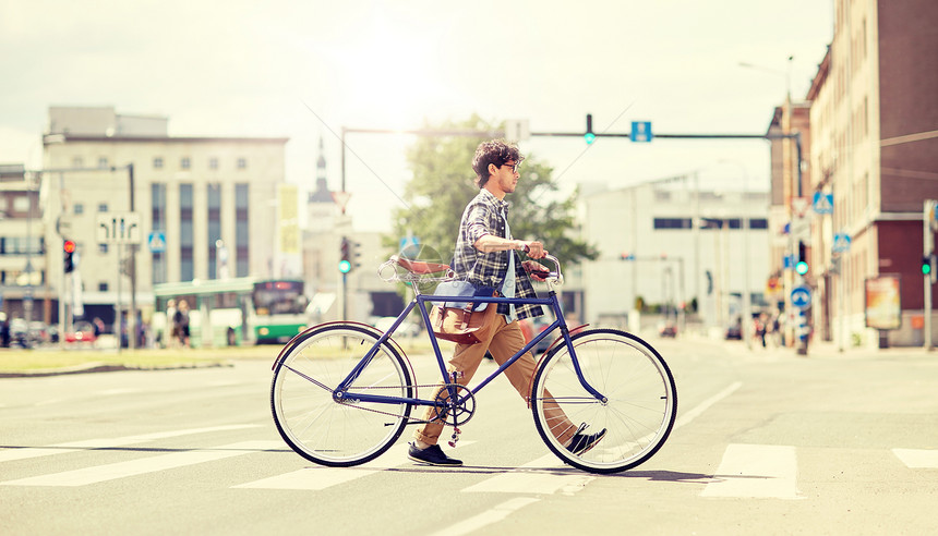 人,风格,城市生活生活方式轻的时尚男子肩袋固定齿轮自行车穿越人行横道街上人行横道上骑固定齿轮自行车的轻人图片