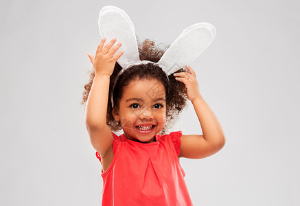 兔子头童,派道具复活节快乐的非裔美国女孩戴着兔子耳朵头巾灰色的背景快乐的小女孩戴着复活节兔子的耳朵背景