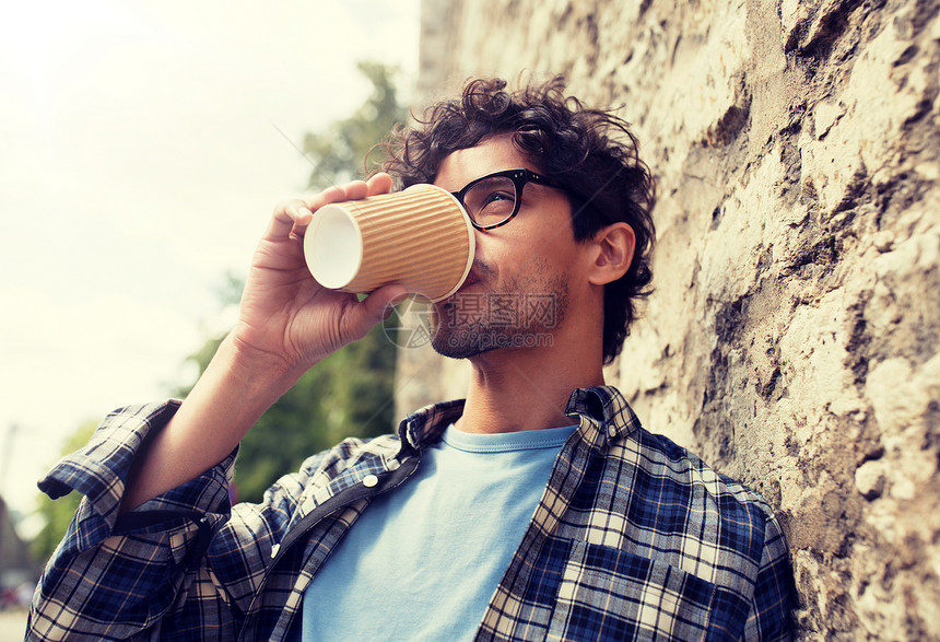 生活方式,饮料人的戴眼镜的人喝咖啡次纸杯石街墙戴眼镜的男人街上的墙上喝咖啡图片