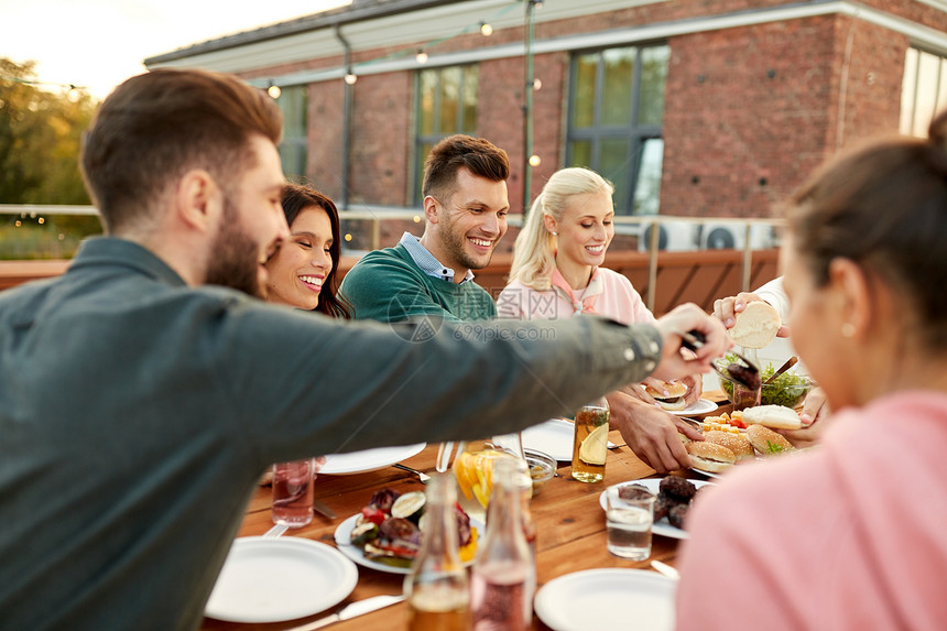 食物休闲人们的快乐的朋友夏天屋顶的晚餐聚会上吃汉堡朋友们屋顶的晚宴上吃汉堡图片