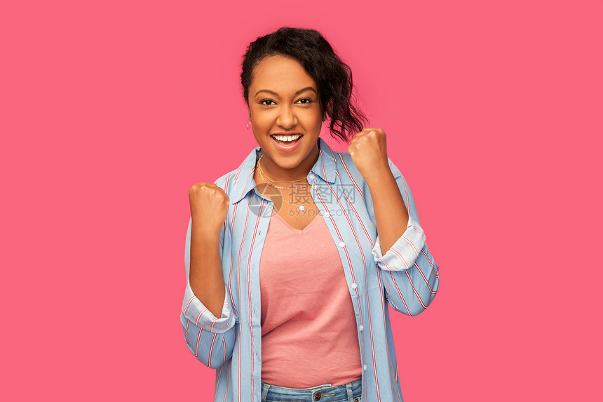 人,手势成功快乐的非裔美国轻妇女庆祝胜利的粉红色背景快乐的非裔美国妇女庆祝成功图片